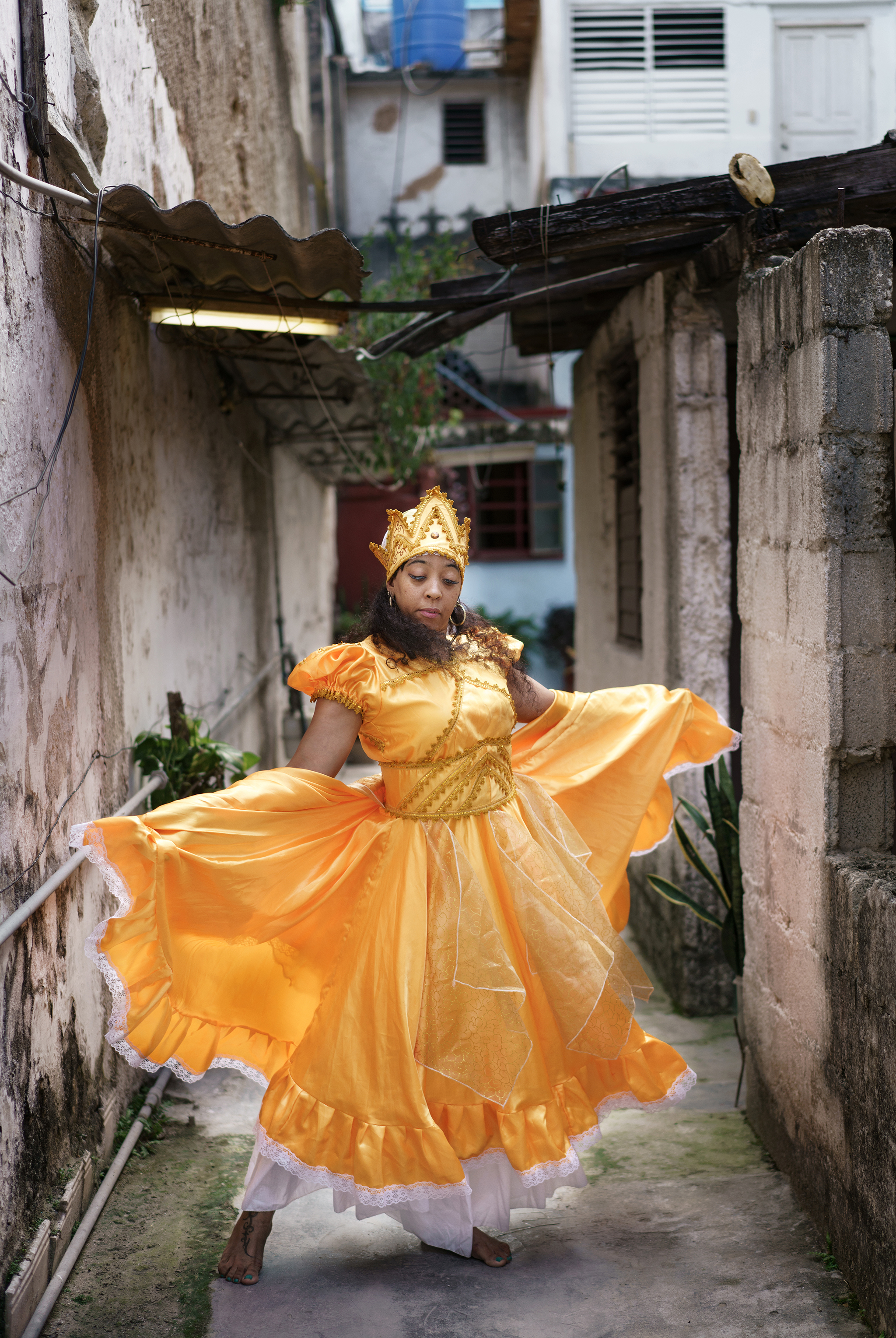 Kuubalainen tanssija nostelee oranssin tanssimekon helmoja.
