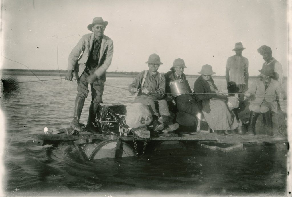 Mustavalkoinen valokuva, jossa monta miestä on lautan kyydissä