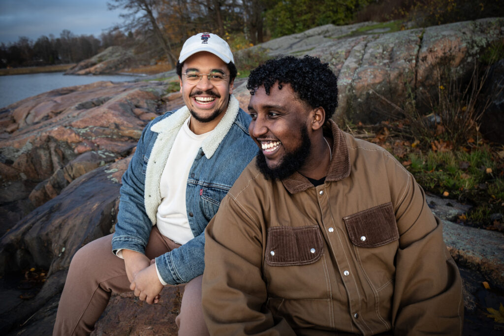 Kaksi miestä istuvat kalliolla ja nauravat.