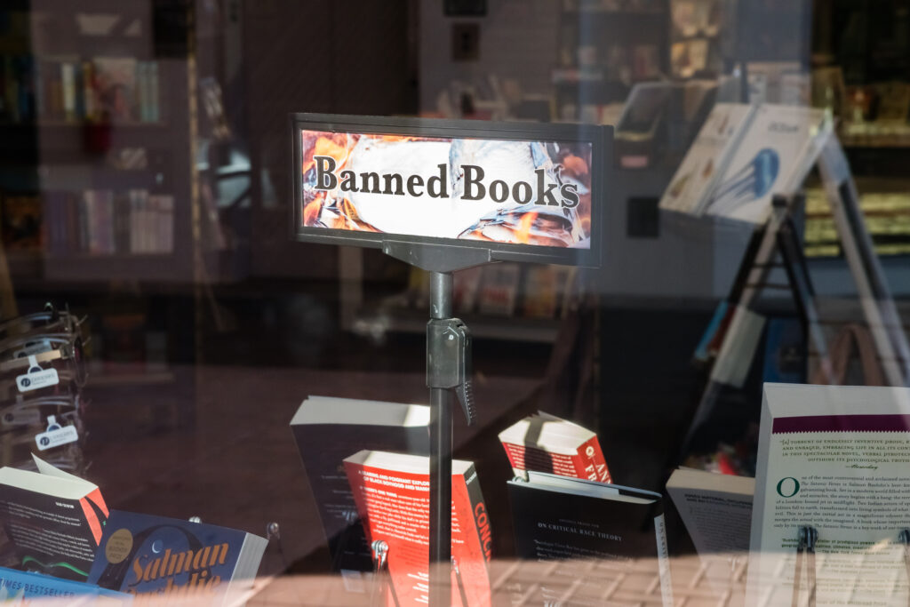 Kuva kirjakaupan ikkunasta, jonka läpi näkyy kirjoja sekä kyltti, jossa lukee "kielletyt kirjat".