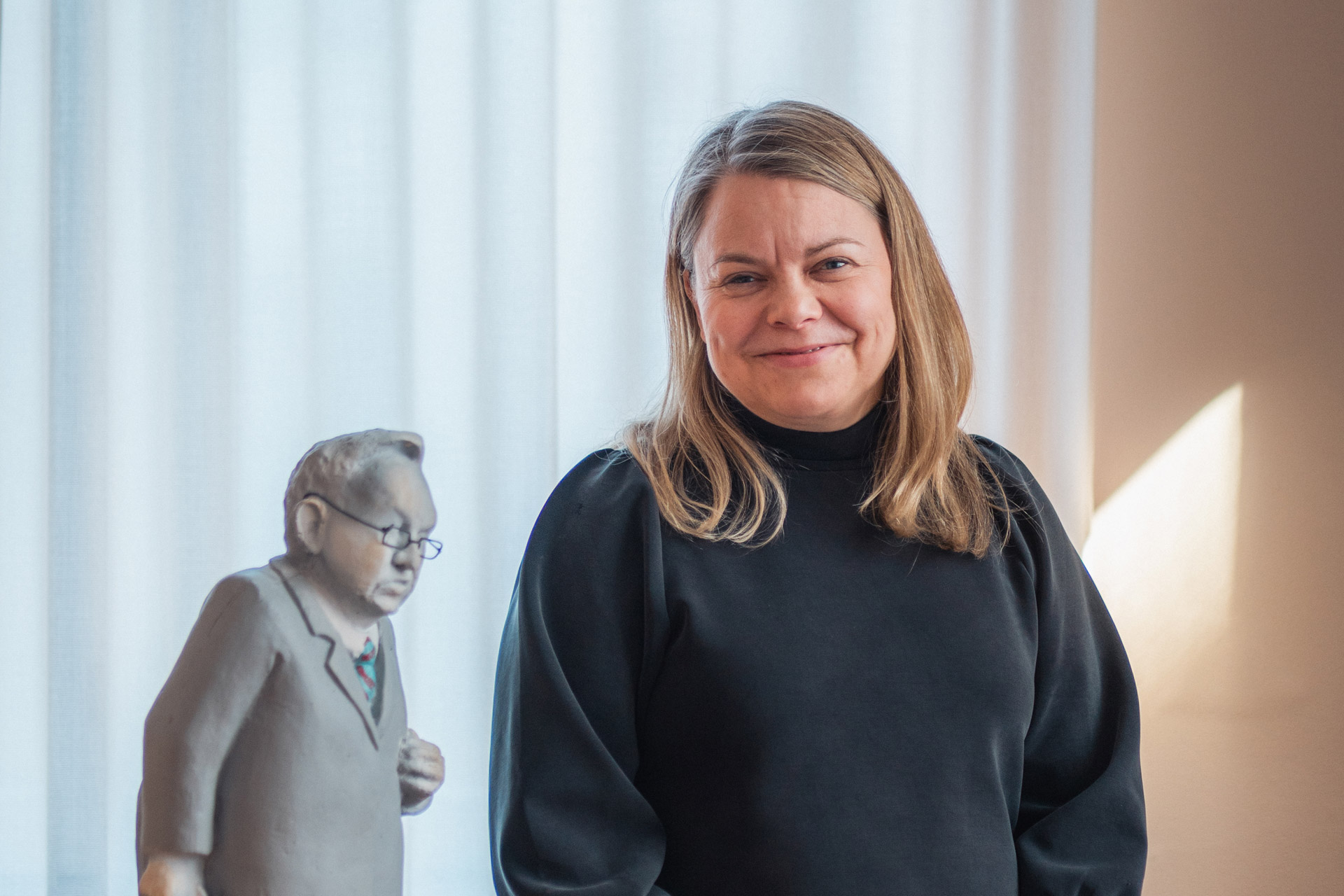 Minna Kukkonen-Karlander puolilähikuvassa, taustalla Martti Ahtisaarta esittävä figuuri.