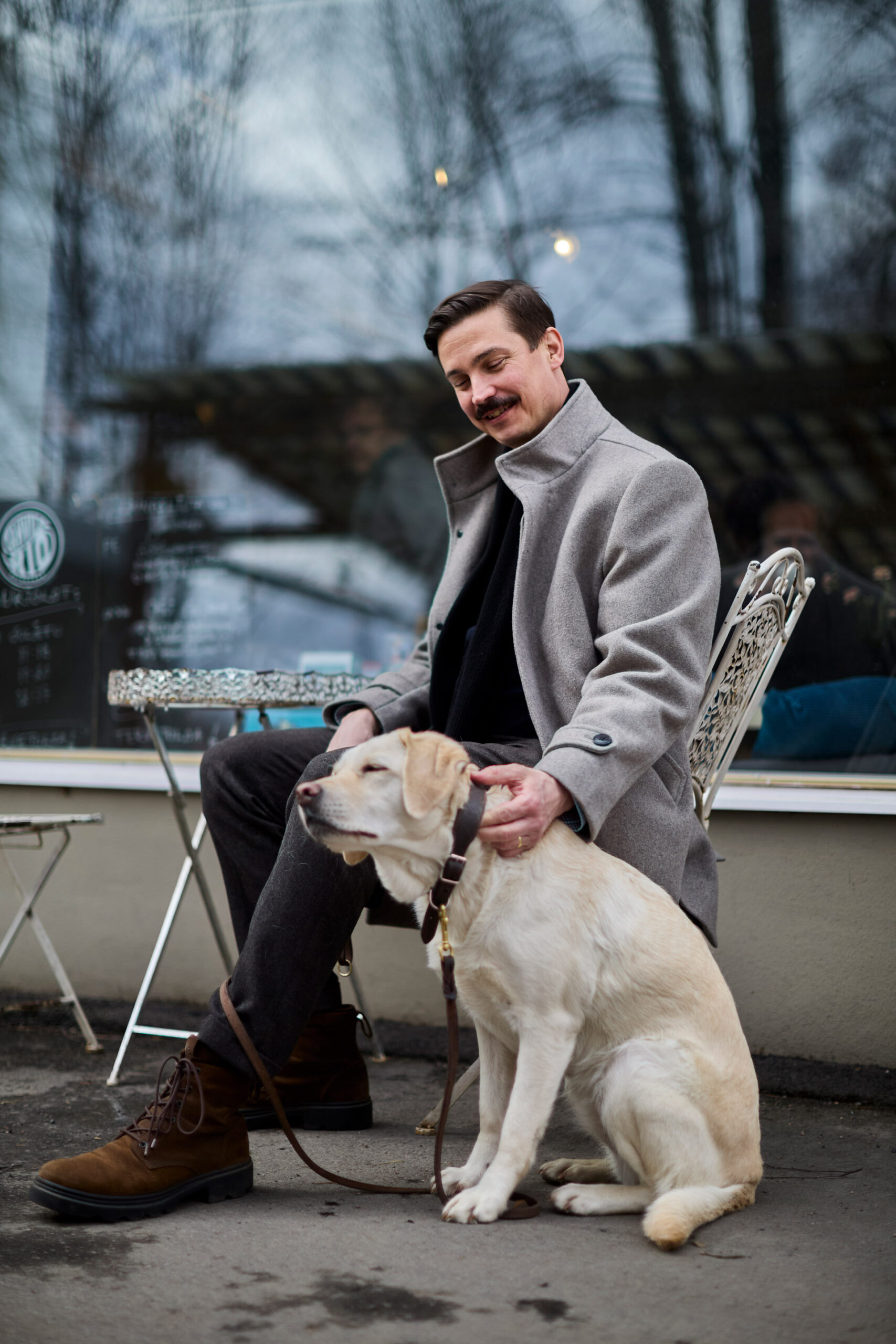 Timo R. Stewart istuu tuolissa ja silittää koiraa.