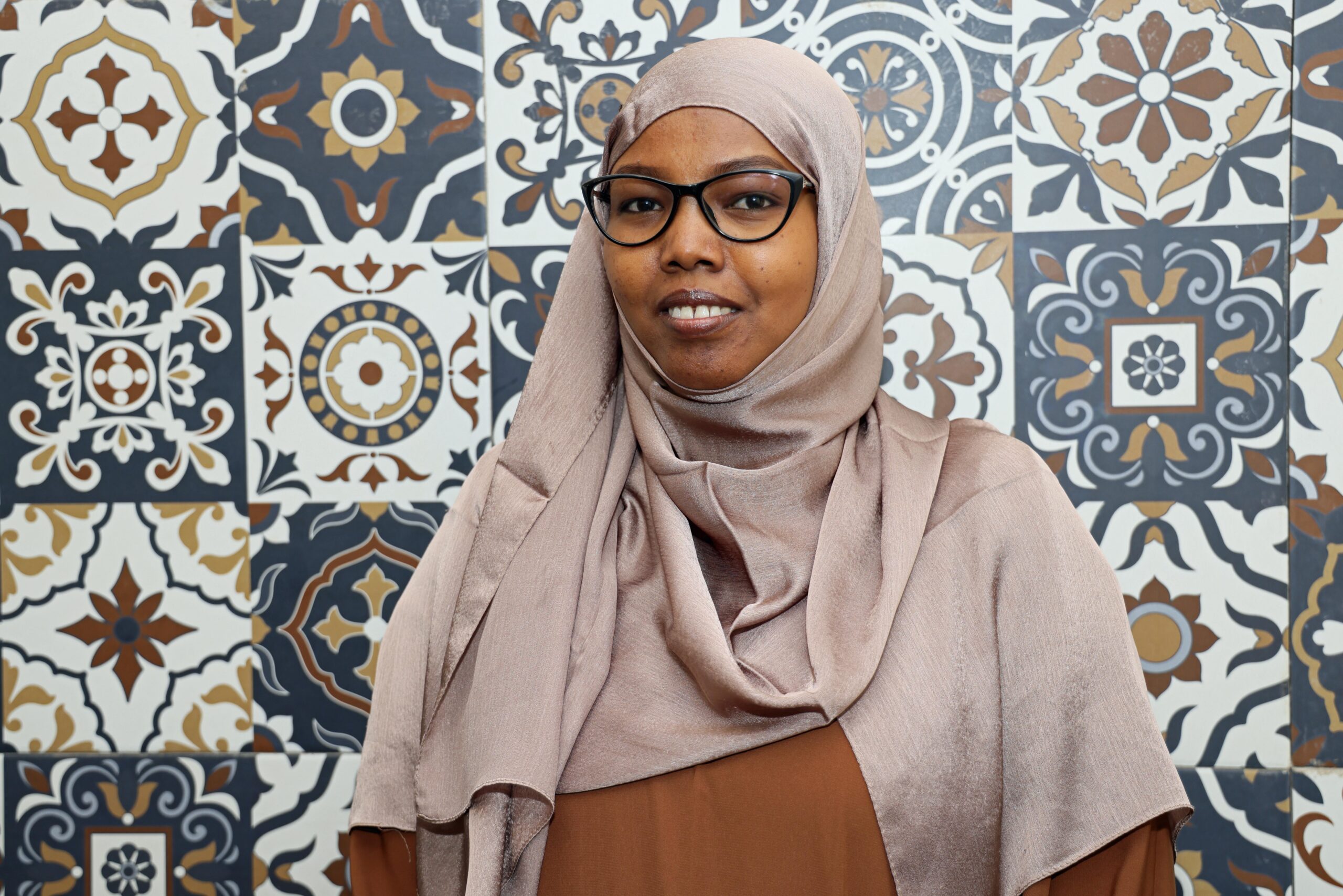 Nesra Osman puolilähikuvassa, taustalla koristeellinen seinä.