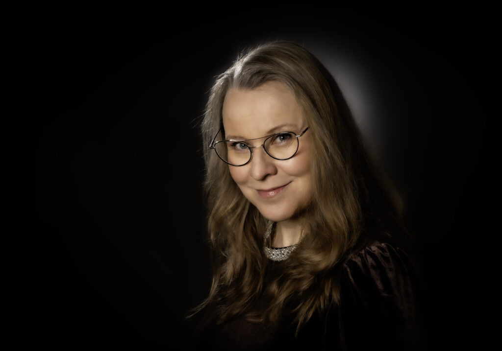 Marjo Näkki mustataustaisessa puoliläihkuvassa.
