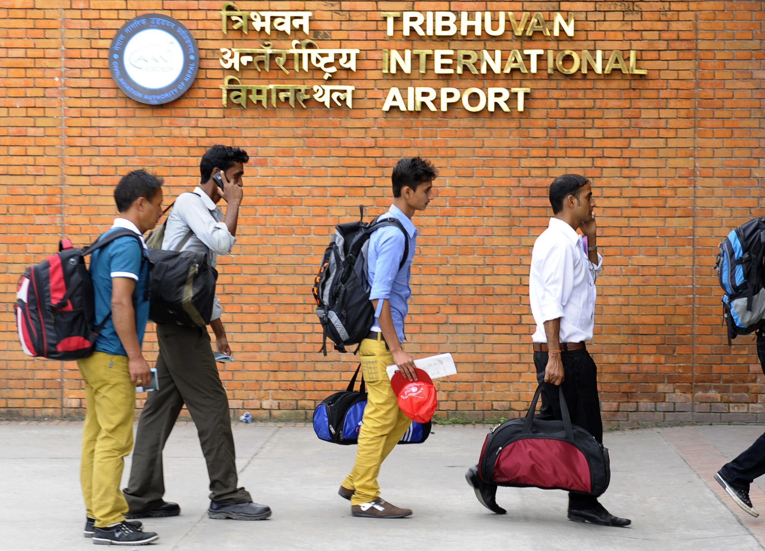 Ihmisiä matkatavaroiden kera. Seinällä teksti Tribhuvan international airport.